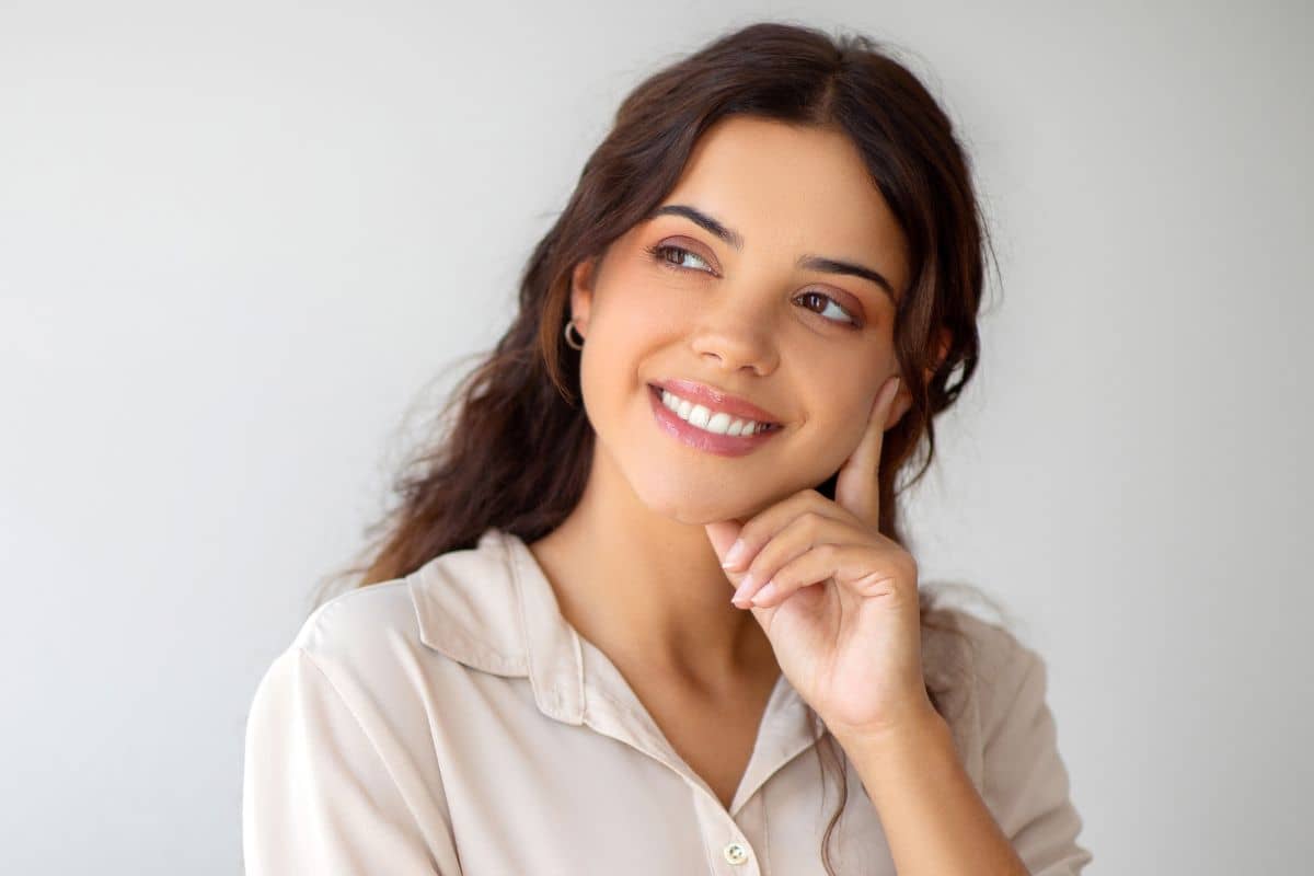 Woman smiling with hand on face, symbolizing consideration of cryotherapy for keloid scar treatment.